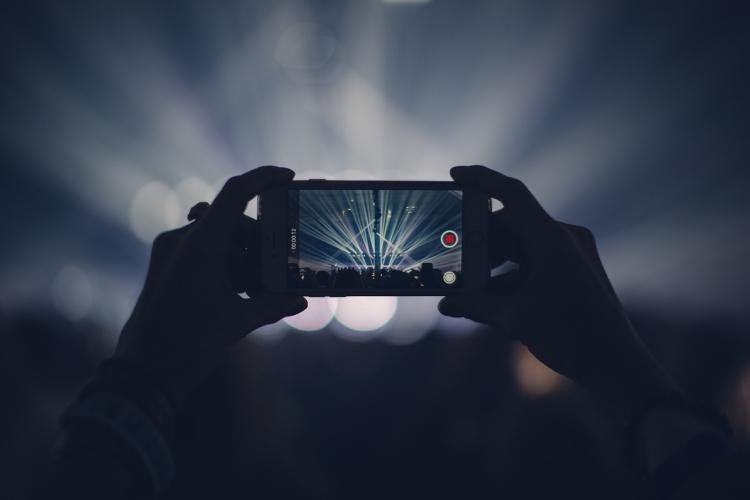Watching a wrestling event online on a smartphone during a live arena show with lights and crowd in the background