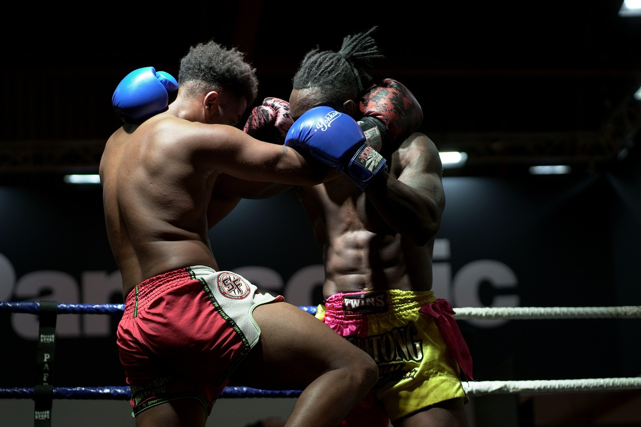 Two professional fighters exchanging close-range strikes in a boxing ring during an intense combat sports match